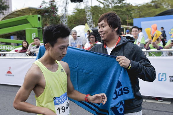 羅嘉仁和李振昌在終點為台北馬拉松跑者送上毛巾和獎牌。(圖/品牌提供)