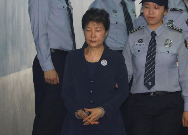 南韓前總統朴槿惠戴手銬出庭應訊，與閨密崔順實同坐被告席。（圖／路透社）