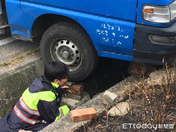 女警蘇姵尹靈機一動，請大家撿拾路邊的磚（石）塊，一塊塊的從水溝底部穩穩的疊起，直到與輪胎胎面接觸為止，再請司機上車催油門，整車遂應聲脫困，現場響起一陣歡呼及掌聲。（圖／台東縣警察局提供）