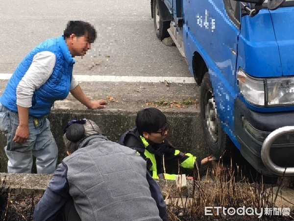 女警蘇姵尹靈機一動，請大家撿拾路邊的磚（石）塊，一塊塊的從水溝底部穩穩的疊起，直到與輪胎胎面接觸為止，再請司機上車催油門，整車遂應聲脫困，現場響起一陣歡呼及掌聲。（圖／台東縣警察局提供）