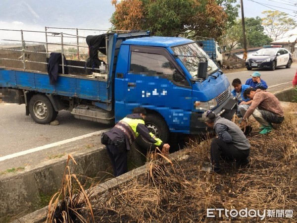 女警蘇姵尹靈機一動，請大家撿拾路邊的磚（石）塊，一塊塊的從水溝底部穩穩的疊起，直到與輪胎胎面接觸為止，再請司機上車催油門，整車遂應聲脫困，現場響起一陣歡呼及掌聲。（圖／台東縣警察局提供）