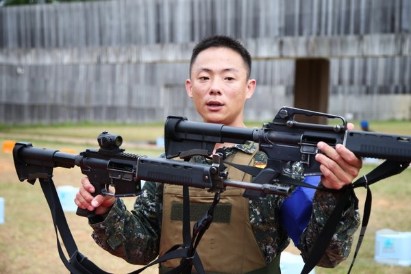 憲訓中心王澤雄士官長說明T91步槍裝置內紅點瞄準鏡，與傳統瞄準方式的差異。（軍聞社記者李一豪攝）