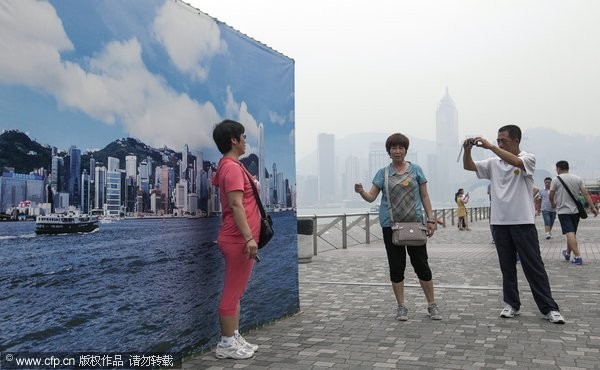 香港空氣污染日趨嚴重，污染指數已經達到了極高的級別，有大陸遊客站在戶外一個巨幅藍天布條前拍照，讓自己宛如身處擁有藍天、白雲的香港。(圖／CFP)