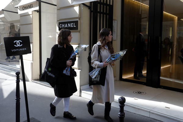 ▲拉格斐（Karl Lagerfeld）逝世，2名女子拿著鮮花到巴黎的香奈兒精品店外致意。（圖／路透）
