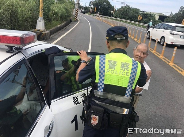 ▲員警扶老翁上警車載回安置。(圖/龍潭警分局提供)
