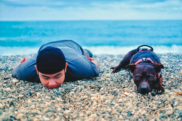 賴聖文帶著米菇環島，圖為去年4月一人一狗趴在花蓮七星潭留影。（賴聖文提供）