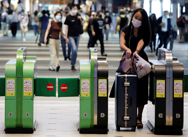 ▲▼日本東京一名攜帶行李箱的旅客通過車站剪票口。（圖／路透）