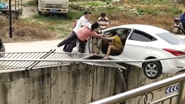 ▲▼熟女「玩命倒車」撞破護欄　「半台車懸空」還拚命狂踩油門！。（圖／翻攝微博）