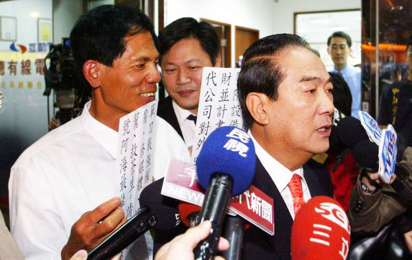 柯賜海常趁機在政治人物受訪或記者連線時在背後高舉標語抗議,成為另類抗議天王。(圖/報系資料照)