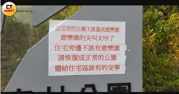 居民怒在森林公園的招牌上貼標語,怒吼住宅區旁不應有遊樂區。(圖/報系資料照)
