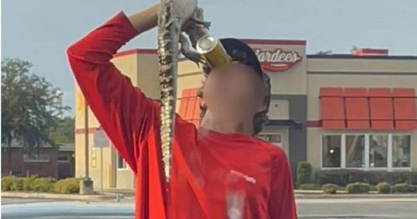 美國佛羅里達州一名少年被拍下，將小鱷魚當成酒罐的底座，抓起暢飲啤酒。（圖／翻攝自推特／@WFLA）