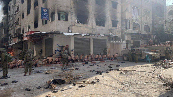 ▲▼     路透社12月8日獲得並核實的照片顯示，巴勒斯坦人被扒光剩下內褲，坐在拜特拉希亞（Beit Lahia）街道上，以色列士兵在旁站崗。 （圖／路透）