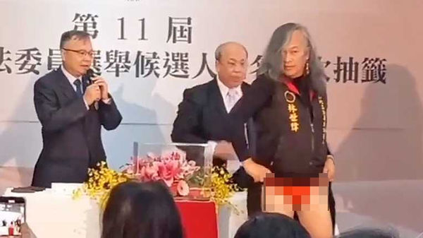 林世偉於立委候選人號次抽籤時,當眾掀起薄長裙露出裡面的紅內褲。(圖/攝自社會事影音)