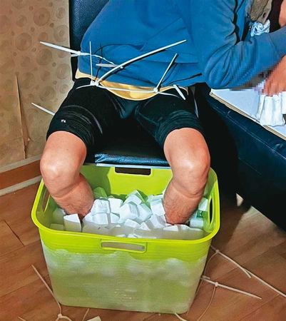 張男的大腿及腰部被束帶固定住,避免他因受不了寒冷把腳從乾冰桶中抬起。(翻攝畫面)