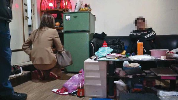 檢警去年底到張男租屋處搜索,張男(右)被要求坐在椅子上等候。(翻攝畫面)