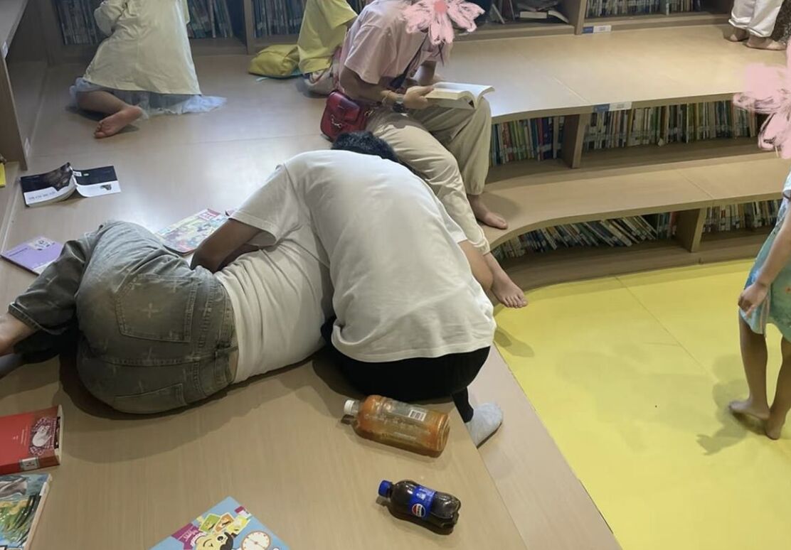 ▲大陸一對情侶在圖書管兒童閱讀區旁若無人的躺地摟抱看片。(圖/翻攝極目新聞)
