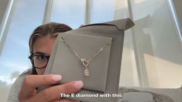 項鍊上有一個鑲滿小鑽石的字母E,是艾瑪名字的縮寫。(翻攝Kai Trump YouTube頻道)