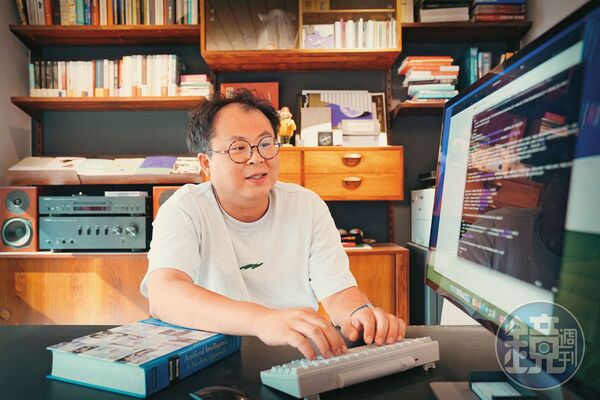 林聖修與我們相約啟明出版社辦公室,辦公桌上放置「以程式設計師理想的鍵位布局」為概念而製作的鍵盤HHKB,手邊原文書是在美念書時,學習人工智慧的課本。