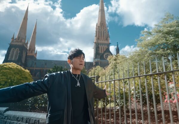 周杰倫在〈恆星不忘 Forever Forever〉MV裡,在墨爾本聖巴特利爵主教座堂外面走路。(翻攝 相信音樂BinMusic YouTube頻道)