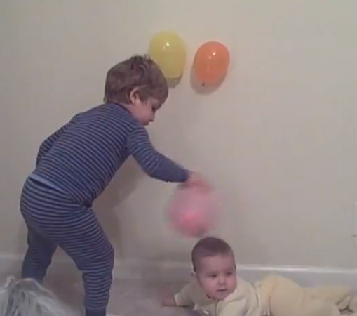 藍斯用氣球磨妹妹的頭，想要變魔術給媽媽看。（圖／取自YouTube）