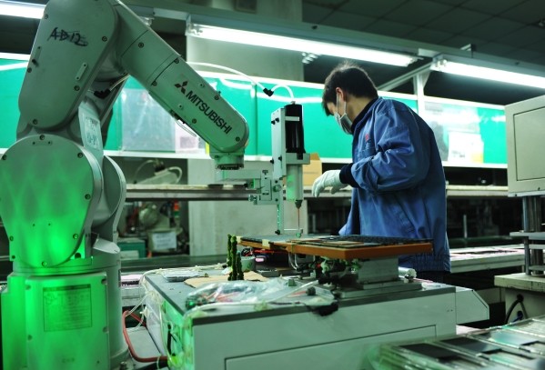 昆山（江蘇），2015年11月30日  機械手在操作筆記本電腦外殼點膠製成工序。（圖／新華社港台部提供）