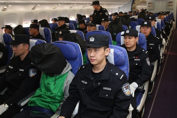 ▲因在肯亞涉及電信詐騙罪遭到羈押的台灣人，昨被中方強行帶走，根據《新華社》最新的照片顯示，這批人員已經飛抵北京機場。根據《新華社》報導，9日遭到肯亞遣返中國的共有10人，今天飛抵北京的則共67人，其中包括45名台灣人和32名中國籍嫌犯。從發布的照片中可以看到，嫌疑人均被套上黑色頭套未露臉，而飛機座位安排上，每位嫌犯左、右各有一名警員「護送」。（圖／翻攝自新華社）