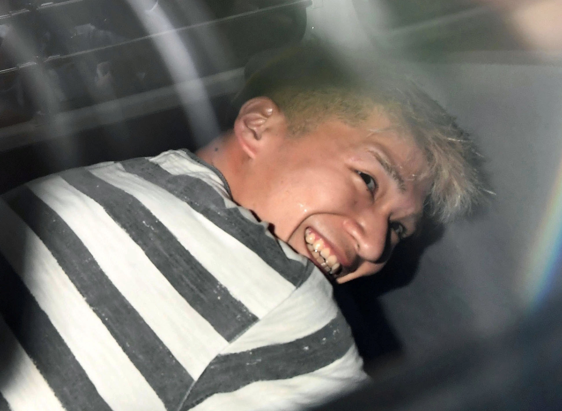 日本26歲殺人犯植松聖被警方移送時，竟露出微笑。（圖／CFP）