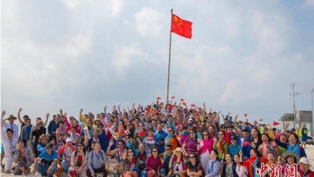 中國遊客在西沙全富島舉行升旗儀式並合影。(圖／翻攝自中新網)