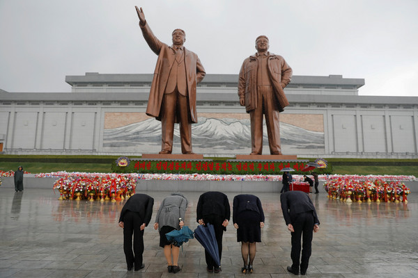 北韓人民帶著鮮花瞻仰金日成銅像。（圖／路透社）