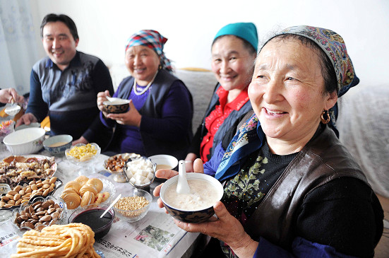 哈萨克族妇女库潘(右一)在家中用「纳吾热孜饭」招待客人,庆祝