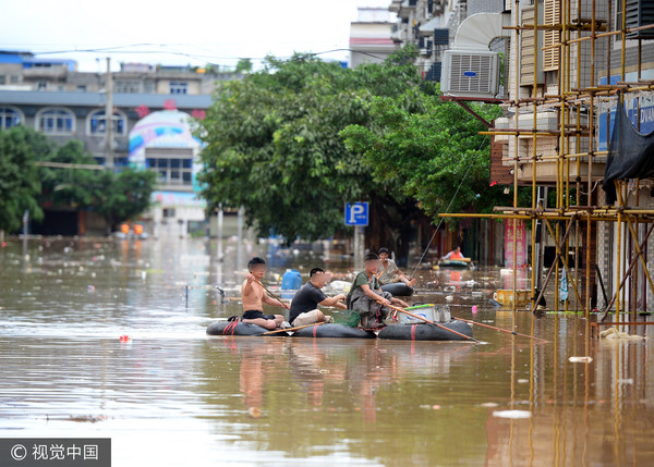 ▲▼2017年7月3日，廣西柳州市雒容鎮的街道被倒灌洪水淹沒，居民乘坐充氣艇在積水路段電魚。（圖／CFP）