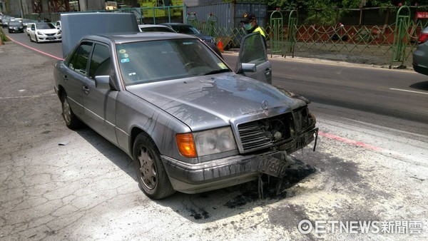 ▲車主開車開到一半，賓士車突然從引擎蓋起火，車主用滅火器自行撲滅，但高溫下，車體溫度仍高，消防隊員佈水線降溫。（圖／記者楊佩琪翻攝）