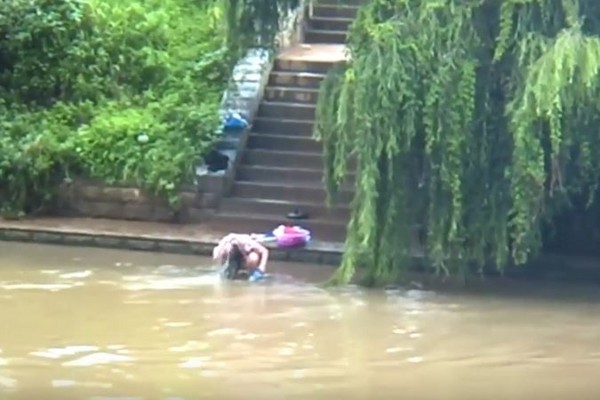 ▲▼雲南省昆明溪水暴漲，大媽只穿內褲與內衣在河邊洗澡。（圖／翻攝自梨視頻）