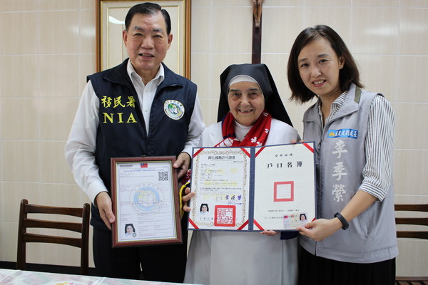 ▲內政部移民署署長何榮村及民政處副處長李季縈，送上定居證及國民身分證。