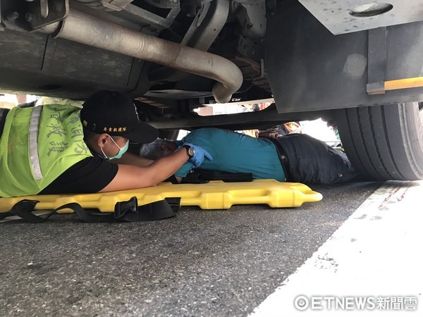 ▲騎士遭垃圾車輾過困車底，消防人員急忙搶救。（圖／記者陳豐德翻攝）