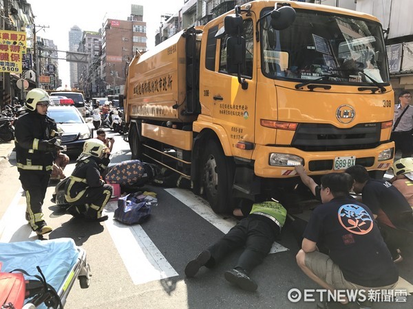 ▲騎士遭垃圾車輾過困車底，消防人員急忙搶救。（圖／記者陳豐德翻攝）