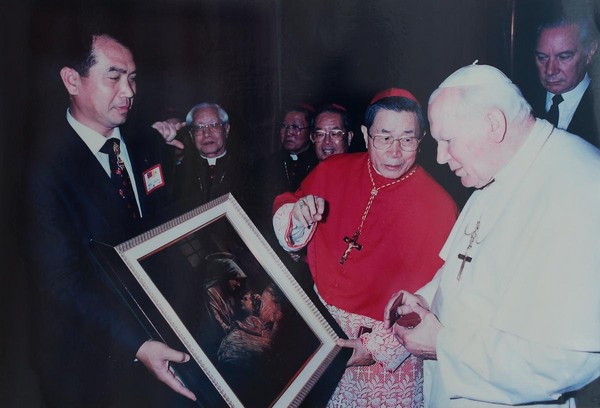 從小接受天主教會接濟長大的洪團樟（左），1995年二度赴羅馬見教宗若望保祿二世（右），中為已逝天主教會樞機單國璽。（一太提供）