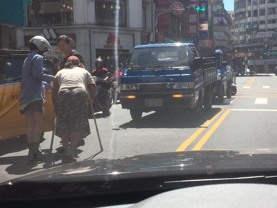 桃園市一名女騎士發現一名行動不便的婦人卡在路中間，立刻下車幫忙扶對方上計程車。路過駕駛見狀拍下暖心過程，伸出車窗對女騎士比「讚」。（圖／翻攝「爆料公社」臉書社團）