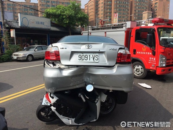 ▲雙載「鑽車陣」遭夾擊　機車卡汽車後輪損毀　2人輕傷。（記者柳名耕翻攝）