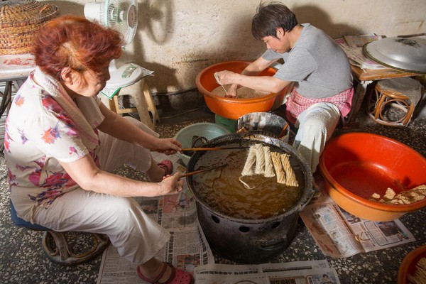 繖子下鍋前還得先用兩根棍子撐住，定型了才能放開。