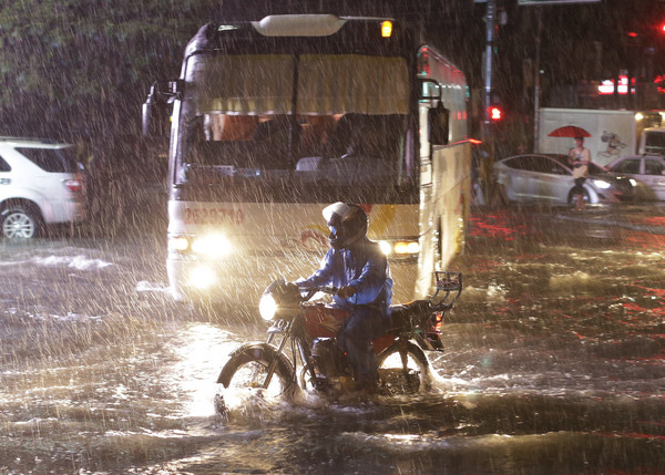 ▲▼一名男子在菲律賓首都馬尼拉冒著大雨騎車。（圖／達志影像／美聯社）