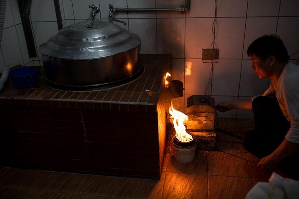 老店至今仍用大灶鍋爐熬煮芋頭等食材，圖為黃志安點燃柴油。