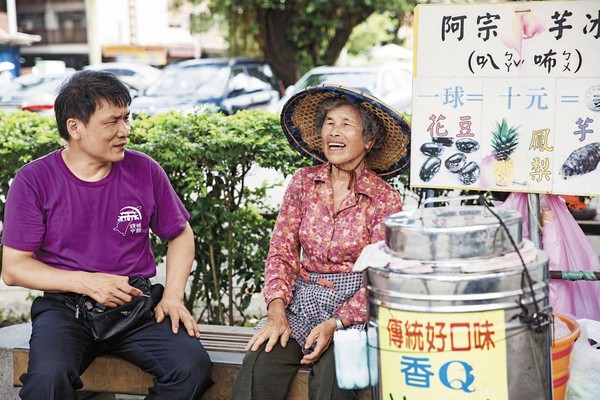 黃志安（左）在頭城火車站前與批發賣冰的阿婆閒聊。