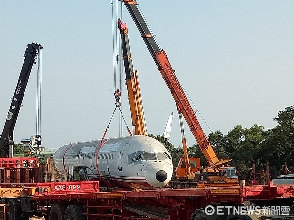 ▲無翅膀的廢棄飛機已拖回業者餐廳預定地，正由吊車高吊掛安置。（圖／記者楊熾興攝）