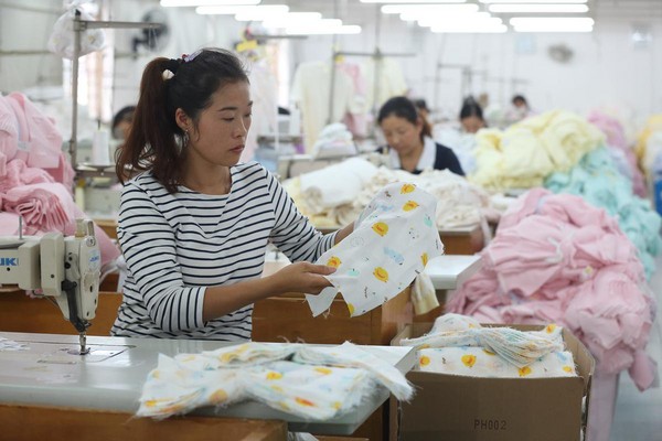 棉品也是品牌主力商品之一，上海工廠女作業員正在車縫棉布衣。