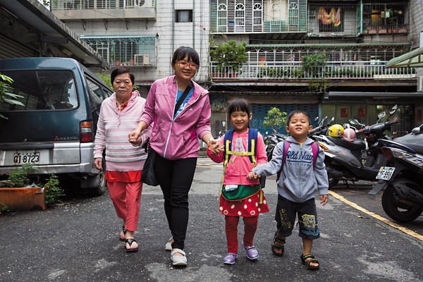 許琇惠（左2）牽著母親（左1）、女兒（右2）、兒子（右1）在家門前的巷子拍照。面對失智症只退不進的情況，許琇惠樂觀看待，她說：「活一天就是賺一天。」
