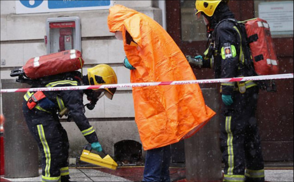 ▲▼消防人員將身穿橘色防護衣表示受過檢測的「民眾」帶到安全區。（圖／翻攝自DAILYMAIL網站）