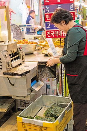 韓國大媽現烘海苔，手法熟練。