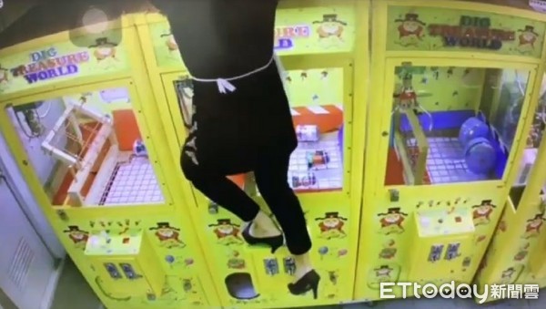 ▲竊嫌踩著高跟鞋爬上娃娃機台，接上電鑽電源準備行竊。（圖／記者陳豐德翻攝）