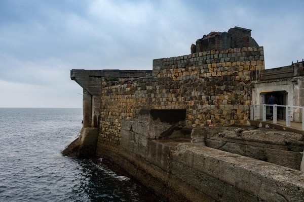 軍艦島的外牆以大石塊砌成，靠近一點還可見到排汙管的出口。